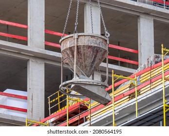 Crane lifting concrete container on construction site. Construction of buildings. Tank with concrete mortar. Monolithic buildings and structures.
