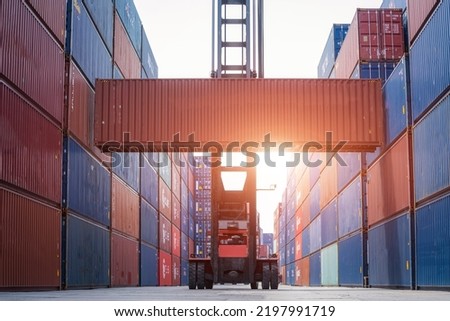 Crane lifting up container and unloading cargo into the import-export zone in yard.