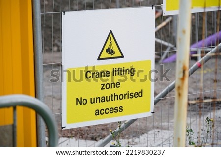 Crane lifting safety sign on construction site fence