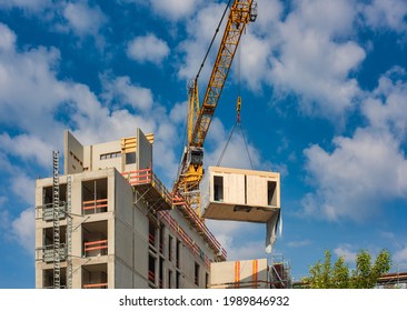 Crane lifting a wooden building module to its position in the structure. Construction site of an office building in Berlin. The new structure will be built in modular timber construction. 