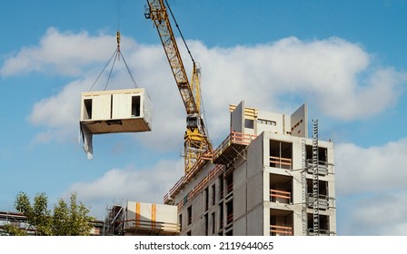 Crane lifting a wooden building module to its position in the structure. Construction site of an office building in Berlin. The new structure will be built in modular timber construction.