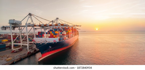 Crane loading cargo container to cargo ship stand by in the international terminal logistic container depot sea port  concept freight shipping by ship at sunset