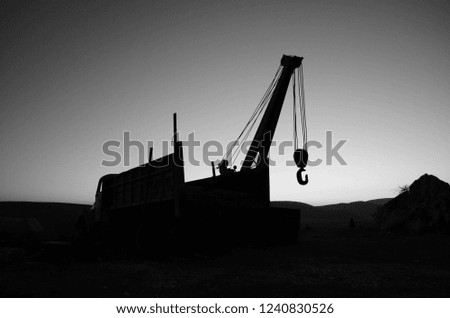 Crane on building site against backlight, grayscale monochrome image
