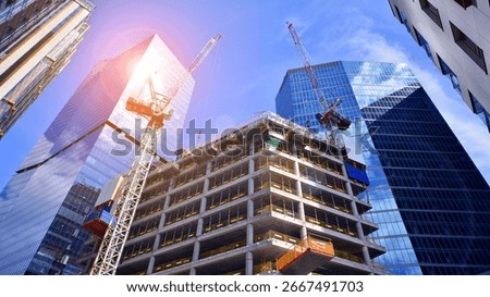 Crane on the construction site in a site surrounded by the high buildings. Office building under construction in the vicinity of high apartment buildings and office building.