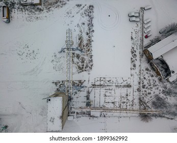 A crane at a snow-covered shipyard. Snowy day, blizzard. Aerial drone view.