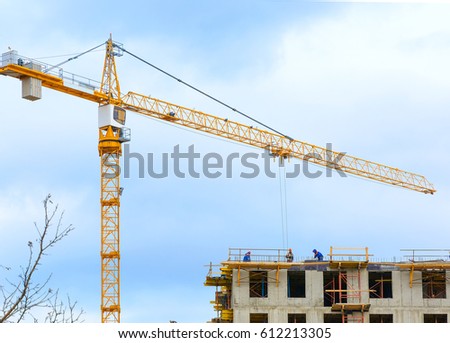 Crane and workers at construction of residental building against blue sky