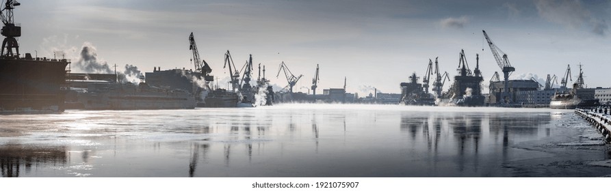 Cranes of of the Baltic shipyard on a frosty winter day, steam over the Neva river, smooth surface of the river, mirror reflection on the water, ships under construction, trawlers, nuclear icebreakers