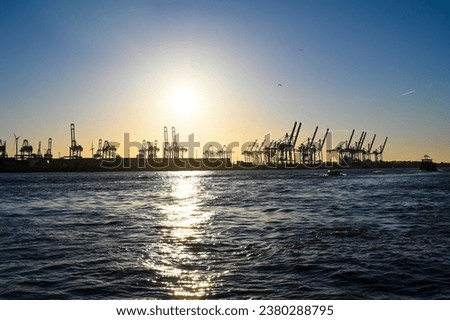 Cranes in harbor at sunset. Hamburg, Germany. Seaport on Elbe river. Jackup rig, Oil platform and Container crane in Dockyard. Ship port. Industry and transport. Shipbuilding.  