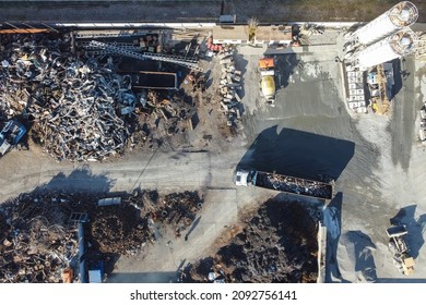 Cranes move metal to compactor. Metal recycling industrial area. Aerial view of machineries working at scrap metal recycling yard. 