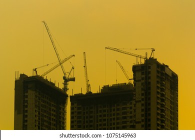 Cranes on the underconstruction building with yellow background