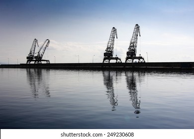 Cranes in the ship's port as silhouettes, in Rijeka in Croatia - Powered by Shutterstock