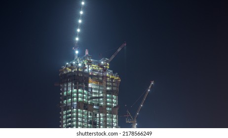 Cranes Working On Modern Constraction Site Works Of New Skyscraper Night Timelapse. Fast Urban Development Consept And Building Activity