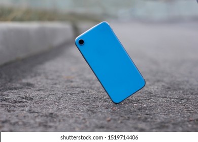 Crash test of a new mobile phone. Gadget falling and crashes on asphalt, floor. Broken smartphone flying down to the ground. Smashed, destroyed, damaged cell phone. Accident with blue device. Failure.