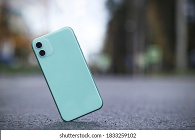 Crash test of a new shockproof mobile phone. Gadget falling and crashes on asphalt, floor. Broken smartphone flying down to the ground. Smashed, destroyed, damaged cell phone. Accident with device.