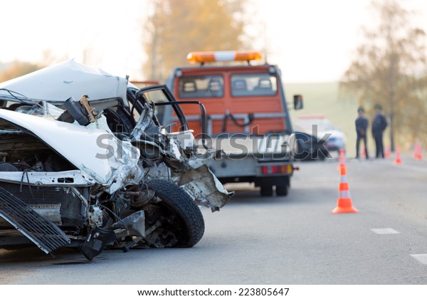 Crashed car automobile collision accident with\
police and tow truck at\
road