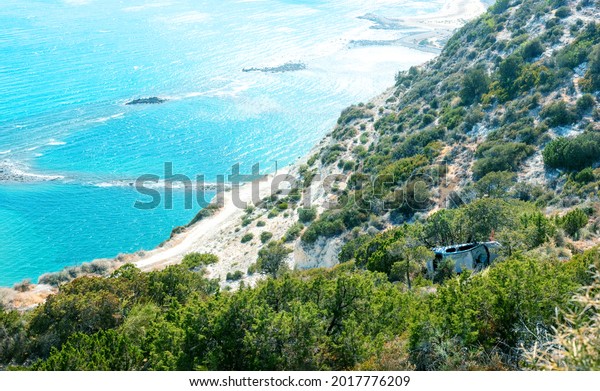 Crashed car\
fallen from a cliff to a seashore. Accident scene in idyllic\
Mediterranean landscape with sea\
beach\
