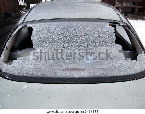 a crashed car heated rear window broken by an\
accidentally cast stone