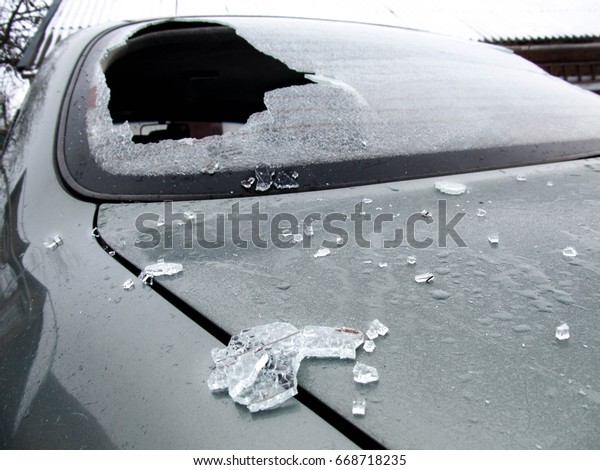 a crashed car heated rear window broken by an\
accidentally cast stone