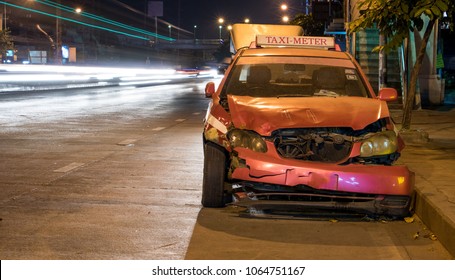 Crashed Car Stands On A Road In The City Center. Damaged Taxi In The Night City.