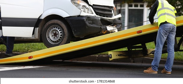 Crashed minibus is loaded onto tow truck after an accident. Evacuation and towing services concept