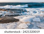 Crashing Waves Against Icy Shores Under Clear Skies at Sunset