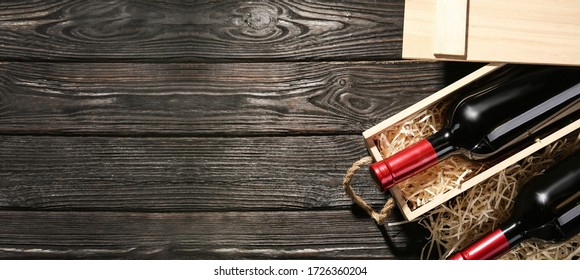 Crate and bottles of wine on wooden table, flat lay with space for text. Banner design
