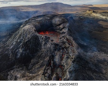 Crater of an active volcano before eruption. Landscape on the Reykjanes Peninsula of Iceland. Liquid lava in the mouth of the volcano crater. Puffs of smoke and steam around the crater