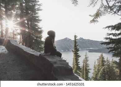 Crater Lake Viewing - Woman Sitting Alone Gazing At Crater Lake - Sun Star And Trees - Wide Landscape Orientation