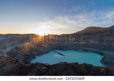 Crater of the Poas volcano at sunrise surrounded by volcanic rocks in the Poas Volcano National Park in the Alajuela province of Costa Rica