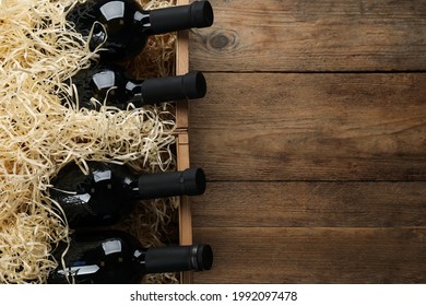 Crates with bottles of wine on wooden background, flat lay. Space for text