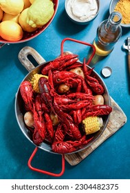 Crawfish boiled Louisiana,with corn on the cob, potatoes. Crawfish boiled in Cajun seasonings and herbs.with beer, New Orleans, Cajun or Creole cuisine, blue background                             - Shutterstock ID 2304482375