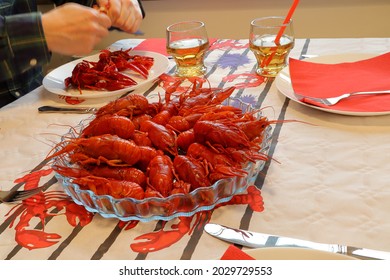 Crawfish party. Crayfish at transparent plate. Popular Swedish tradition in August or September. White paper with symbols of cray fish on. Selective focus. Blurry hand in background. Stockholm, Sweden