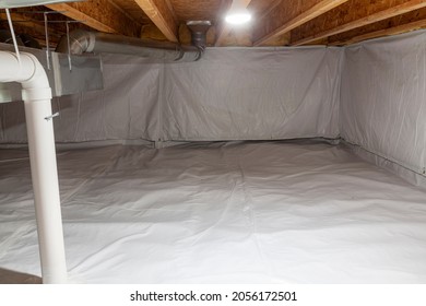 Crawl space fully encapsulated with thermoregulatory blankets and dimple board. Radon mitigation system pipes visible. Basement location for energy saving home improvement