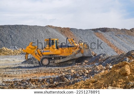Crawler dozer working on construction site or quarry. Mining machinery moving clay, smoothing gravel surface for new road. Earthmoving, excavations, digging on soils