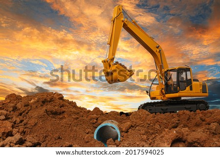 Crawler excavator is digging in the construction site pipeline work on sunset sky background