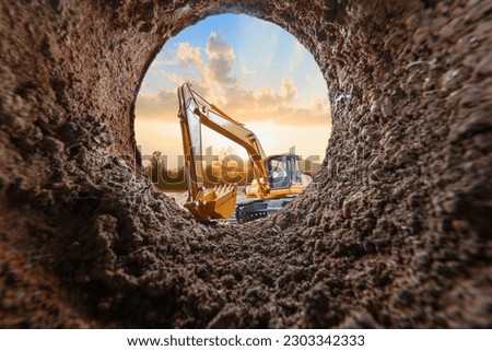 Crawler excavator are digging soil in the tunnel construction site. With a  sunset background