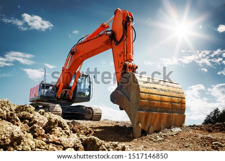 Crawler excavator front view digging on demolition site in backlight