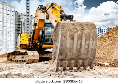Crawler Excavator Machine Unloading Sand or Soil at Construction Area Background. Close-up of an excavator bucket with an extended boom. Rental of construction equipment. earthworks contractor