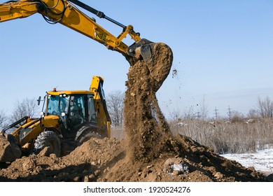 Crawler excavator. The excavator in the process of work digs out the earth and pours it onto the site. Works on a clear winter day against the blue sky.