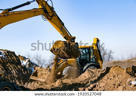 Crawler excavator. The excavator in the process of work digs out the earth and pours it onto the site. Works on a clear winter day against the blue sky.