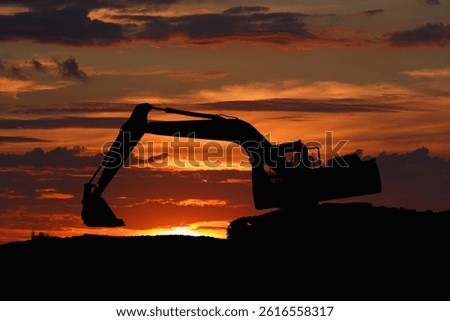Crawler excavators silhouette are digging the soil in the construction site with bucket lift up. on  sunset  background