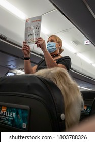 Crawley, Sussex, UK- 08.05.2020 : an air stewardess wearing a face mask demonstrating the air safety procedures during a Easyjet flight. - Shutterstock ID 1803788326