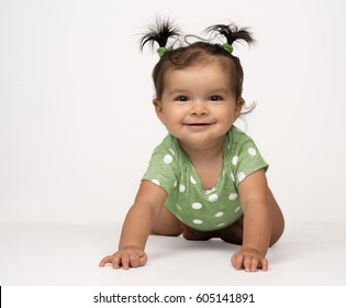 Crawling, mIxed race, baby girl in green onesie on white background