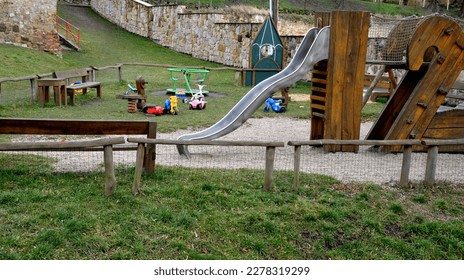 crawling wooden attraction on the sandpit. children have a stainless steel slide and rope nets for climbing and for greater safety on the bridge. stone sandstone wall in the background of kindergarten - Shutterstock ID 2278319299