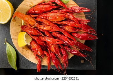 Crayfish, Crawfish closeup. Red boiled crayfish in wooden plate with herbs and lemon on stone slate dark background. Crawfishes. Fresh Lobster closeup.  - Shutterstock ID 2254852531