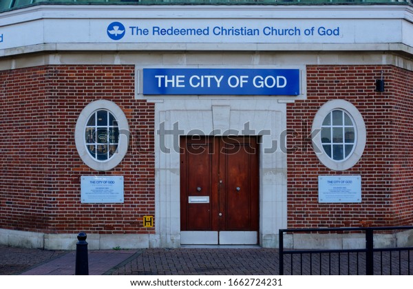 Crayford, Dartford, United Kingdom -\
October 1, 2019: Facade of The Redeemed Christian Church of God The\
City of God showing signage on a red bricked\
wall.
