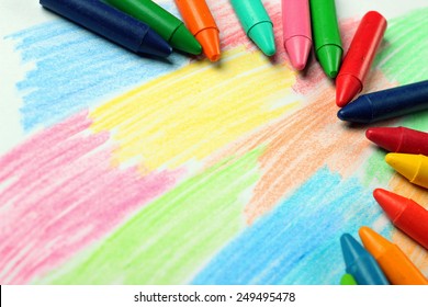 Crayons lying on an abstract hand drawing background. Selective focus, copy space background