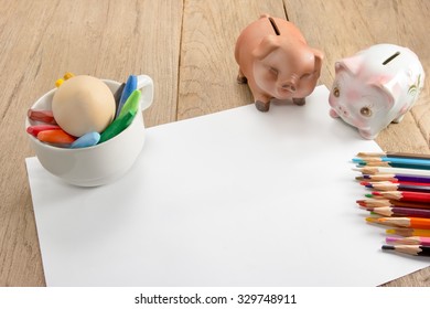 Crayons And Piggy Bank On A Sheet Of Paper