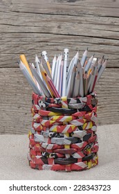 Crayons in a recycled newspaper jar against wooden background 
