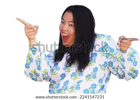 Crazy Asian Filipino attractive young woman in floral blouse strikes a funny, crazy pose while pointing, laughing and looking goofy